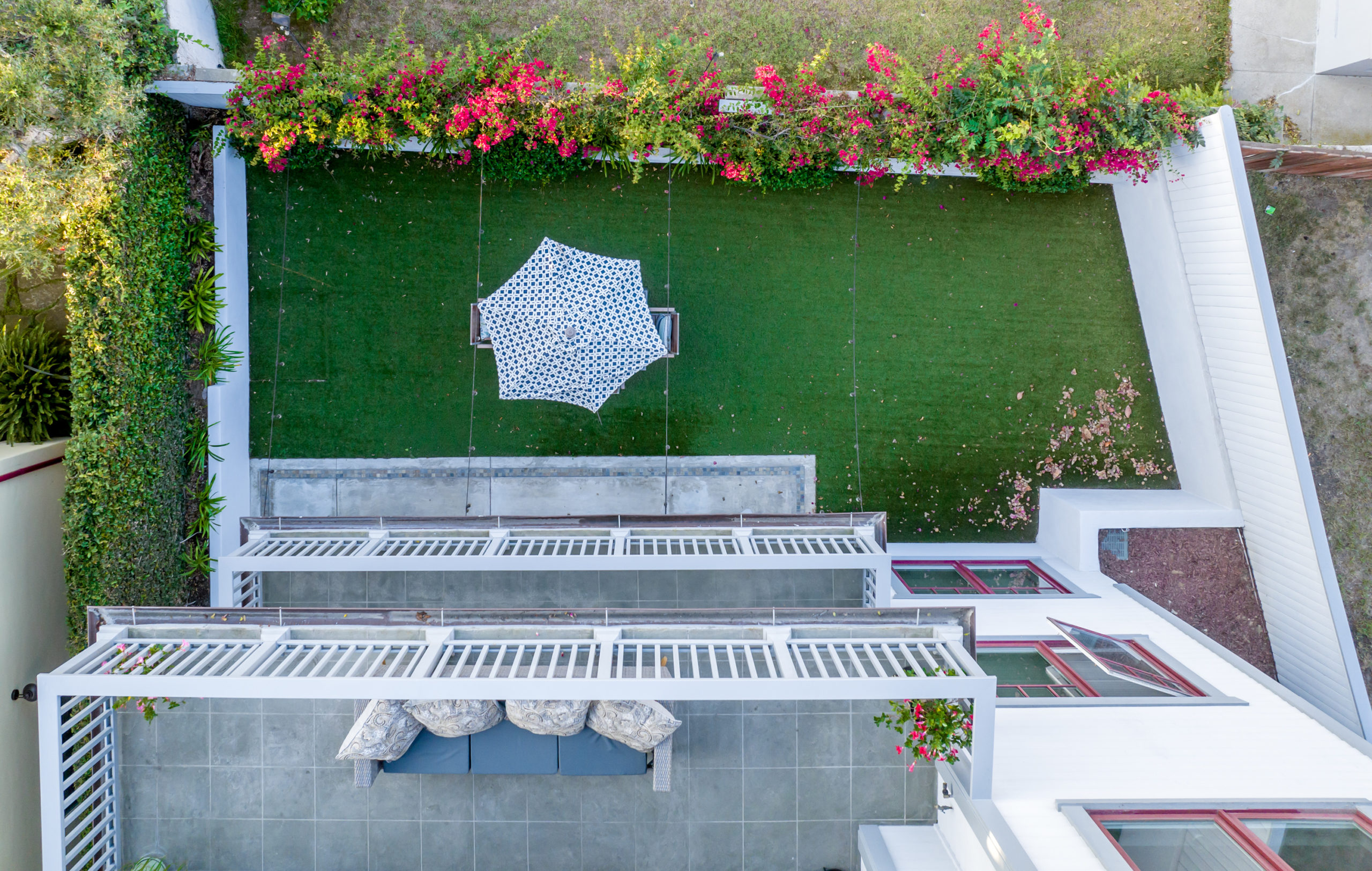 looking down from three stories above on a house and it's balconies and backyard