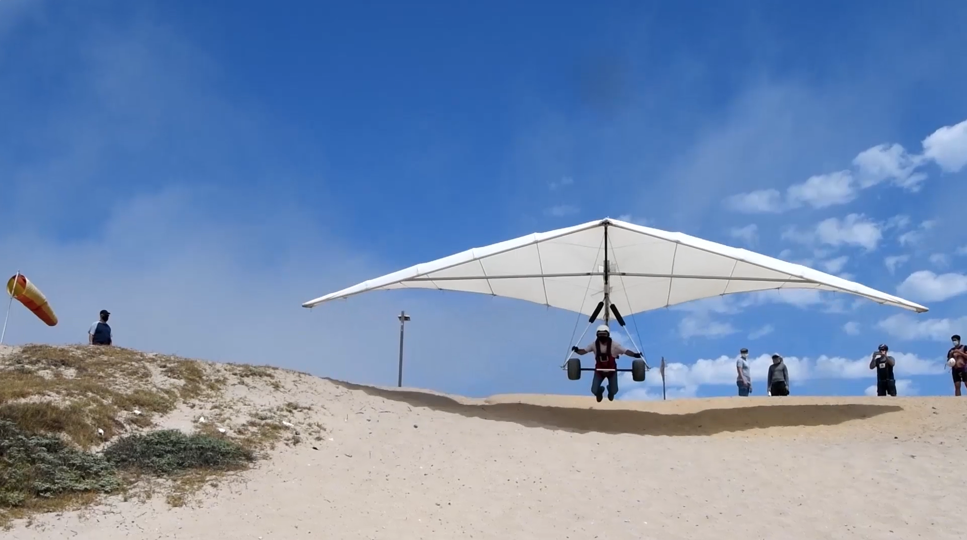 hang glider taking off from beach dune