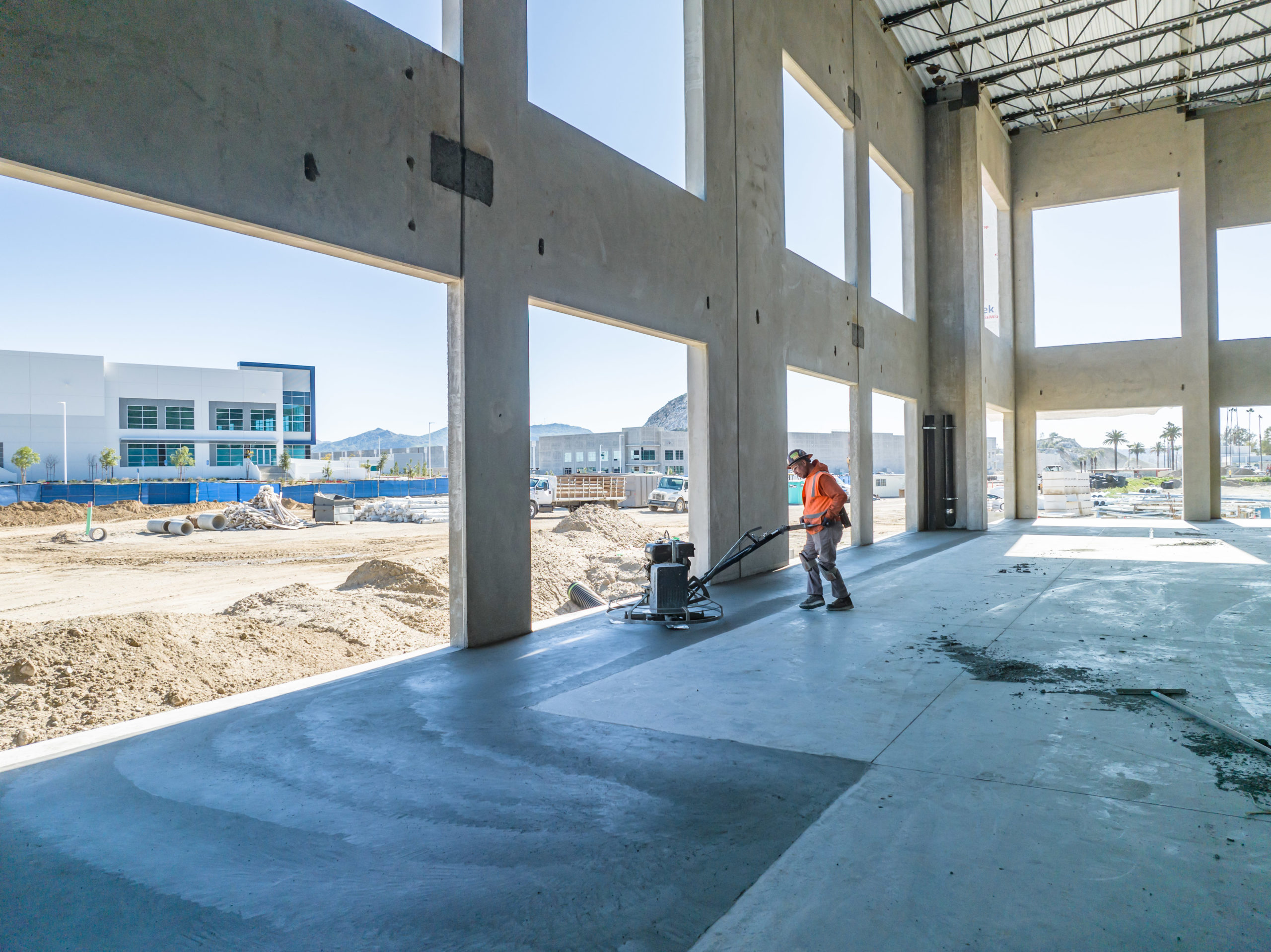 Worker smoothing out freshly poured concrete inside a building